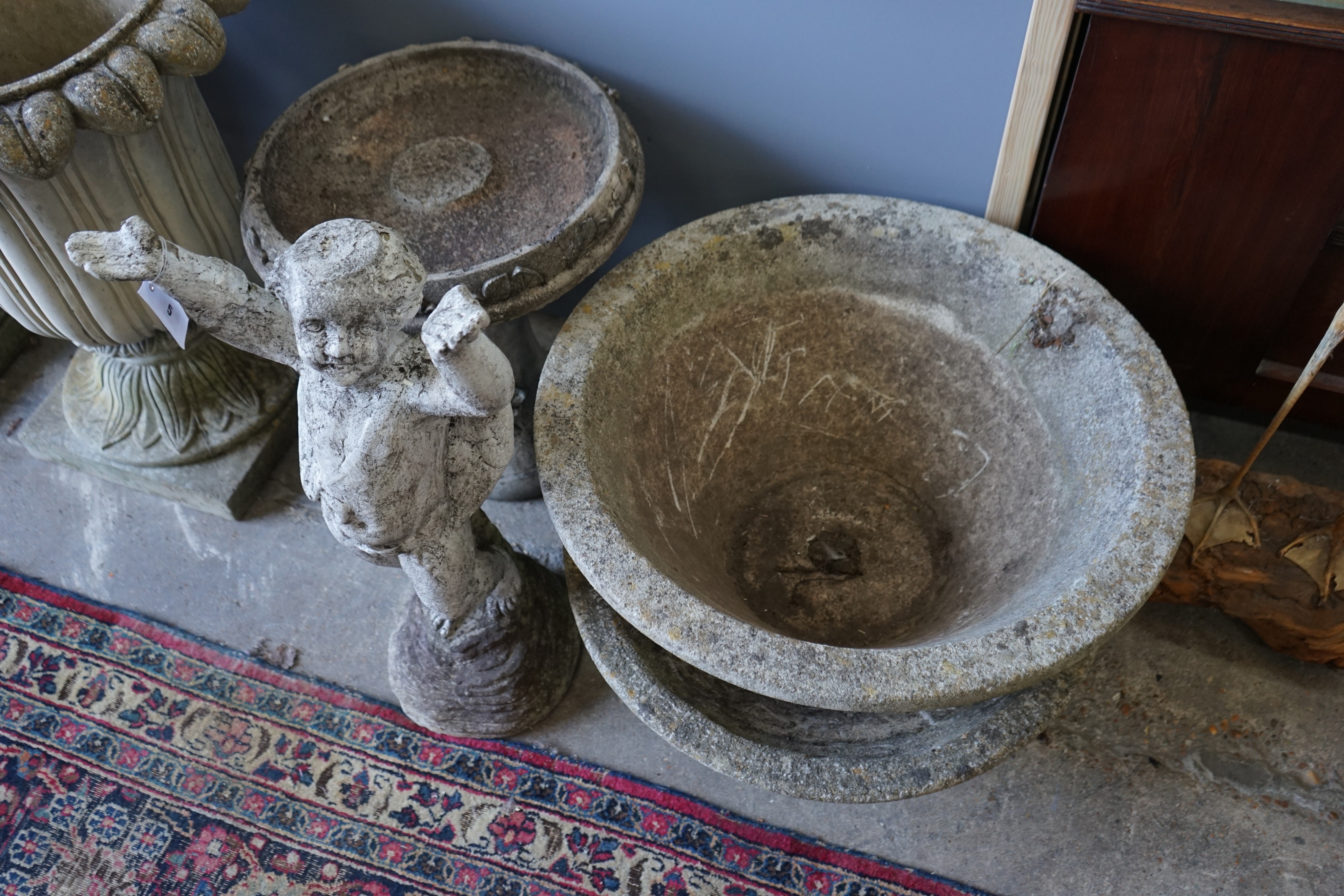 A circular reconstituted stone bird bath, height 50cm, a pair of circular planters and a cherub ornament